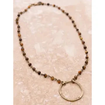 Necklace with beads and a circular pendant on a textured beige background