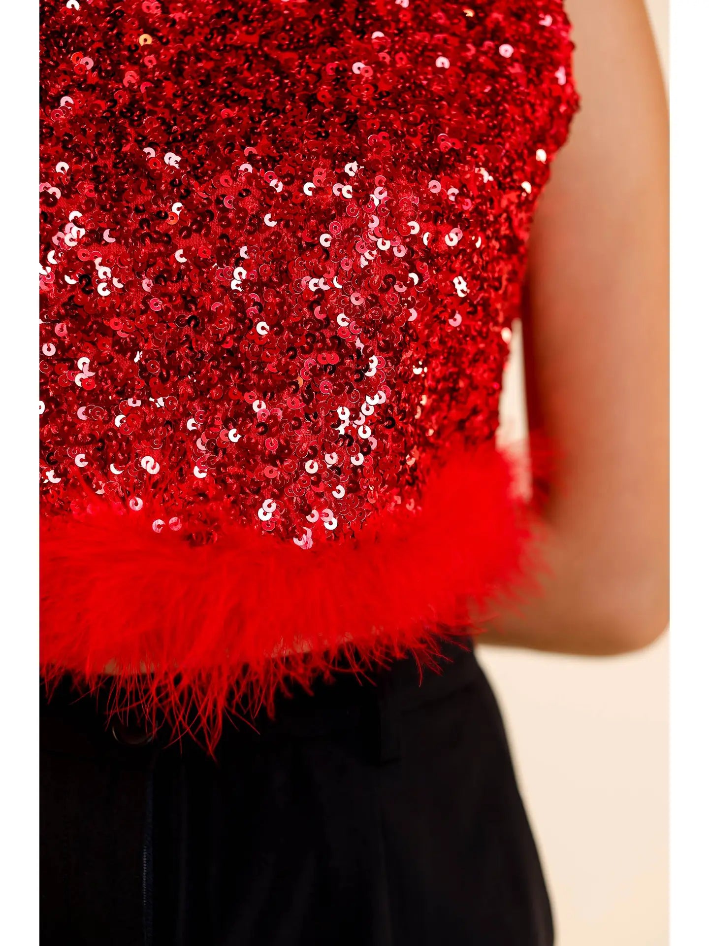 Sequin Feather Crop Top is a bold and glamorous statement piece. Featuring shimmering red sequins and a playful feathered hem.