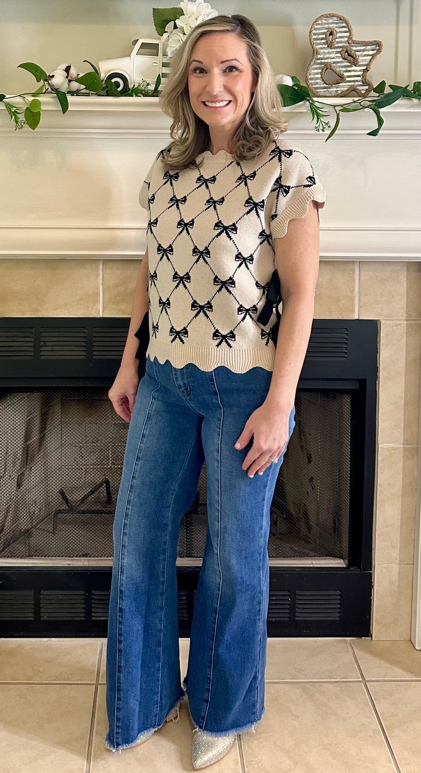 Woman standing in a living room with a fireplace and decorative mantel.