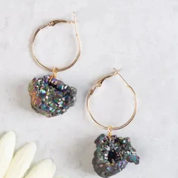 Gold hoop earrings with natural rock-like charms on a light background