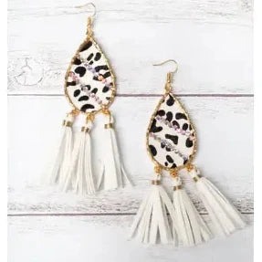 Pair of earrings with leopard print and white tassel design on a light wooden background