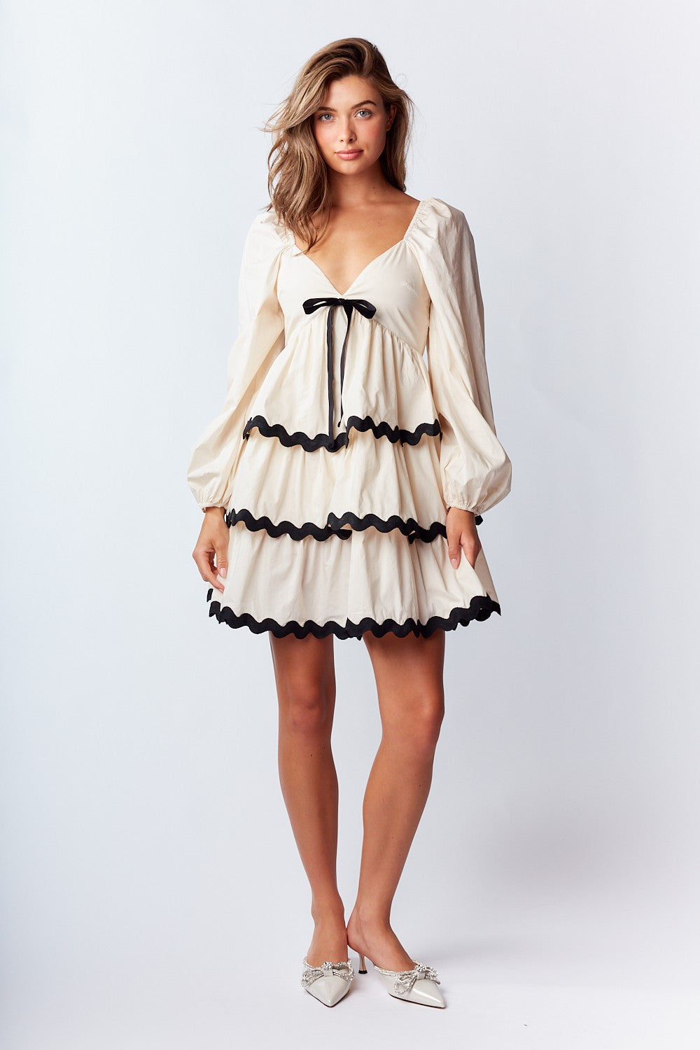 Ric-Rac Mini Dress is a playful and feminine piece that exudes effortless charm. Featuring a deep V-neck with a ribbon tie closure.