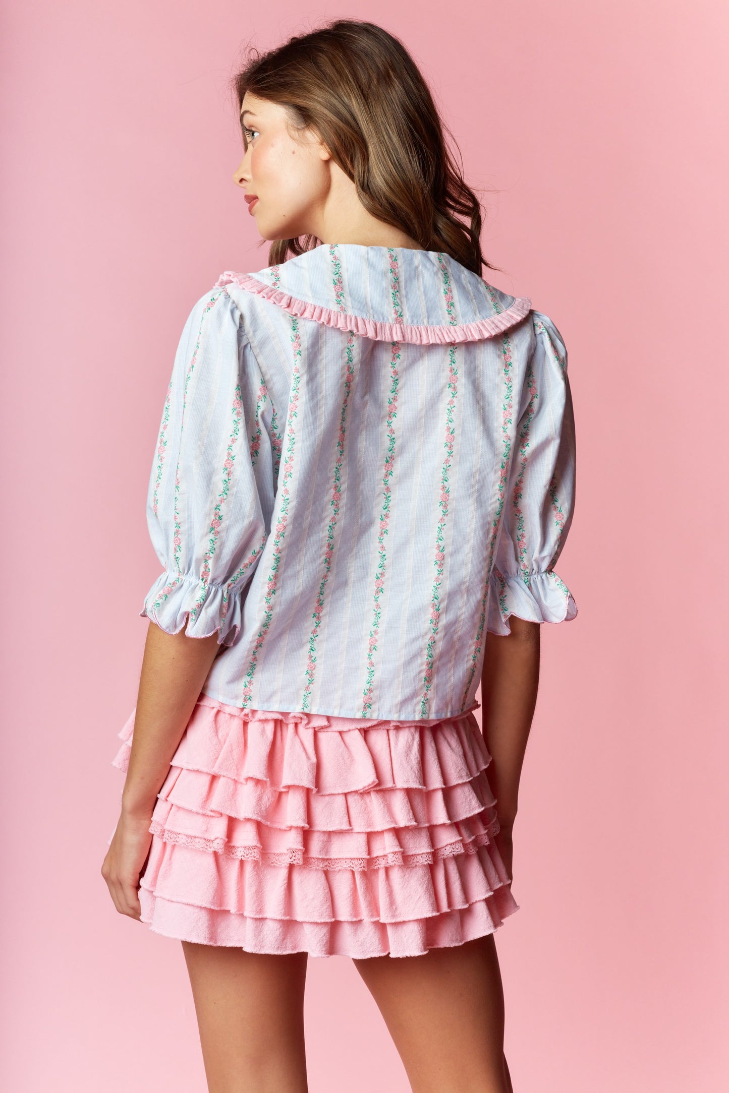 Sailor-Collar Cropped Blouse blends vintage charm with playful femininity. Designed with a relaxed fit and cropped length, this blouse features a sailor-style collar adorned with ruffle trim and delicate floral embroidery on a striped fabric.