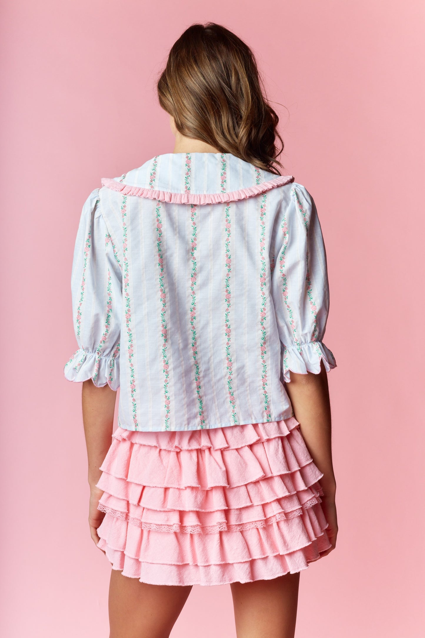 Sailor-Collar Cropped Blouse blends vintage charm with playful femininity. Designed with a relaxed fit and cropped length, this blouse features a sailor-style collar adorned with ruffle trim and delicate floral embroidery on a striped fabric.