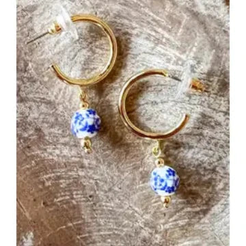 Gold hoop earrings with blue beads on a textured surface