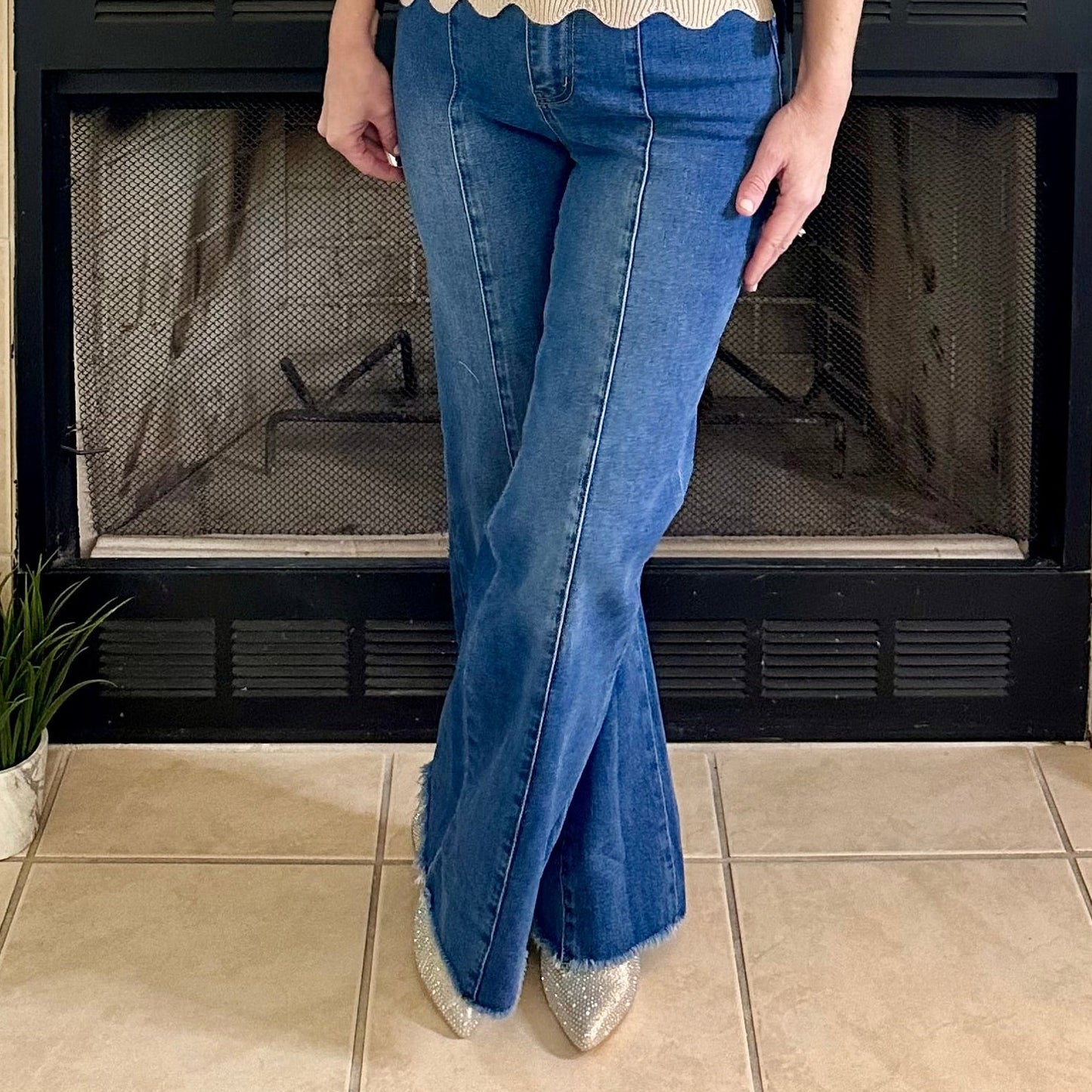 Woman standing in a living room with a fireplace and decorative items.