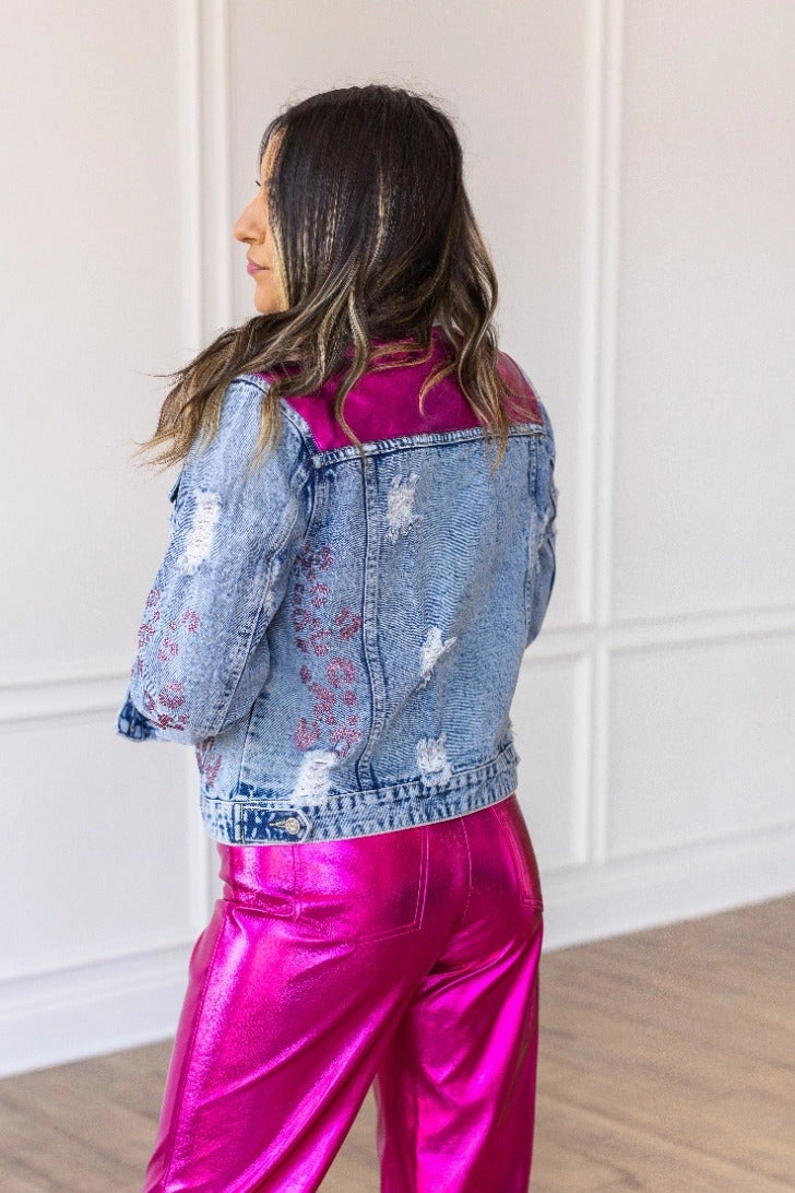 Denim Jacket is a striking blend of classic denim and glamorous details. Featuring a fitted silhouette, distressed touches, vibrant satin panels, and jeweled accents.