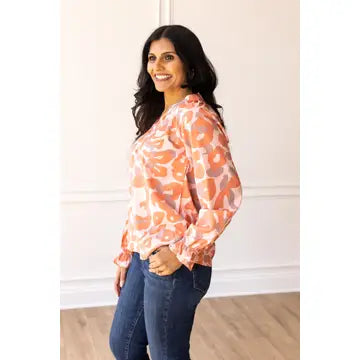 Coral Leopard Blouse. Featuring a relaxed fit, bold coral leopard print, and charming ruffle details on the cuffs.