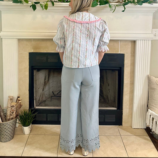 Woman standing in a living room with a fireplace and decorative mantel.