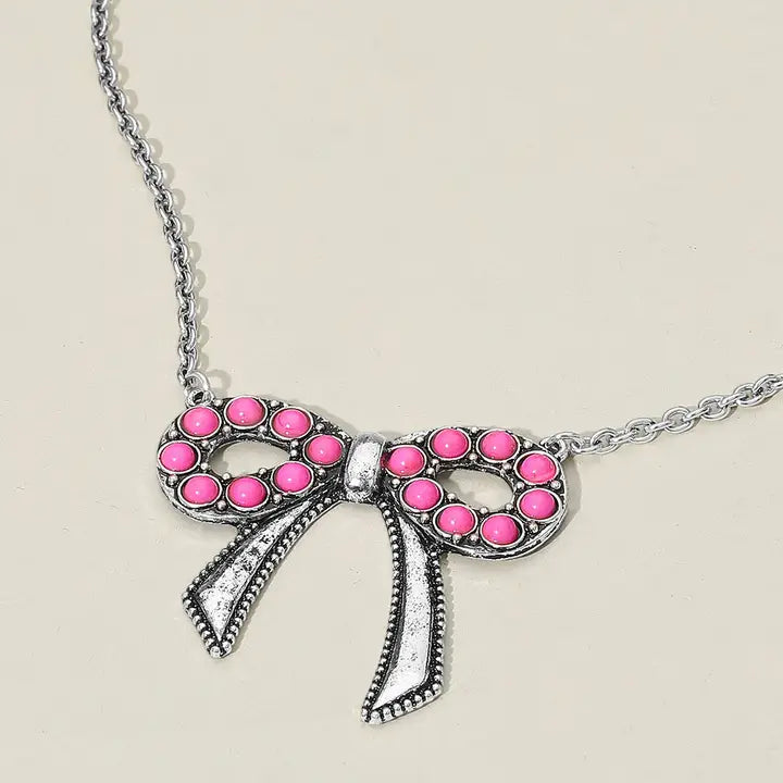 Necklace with a bow-shaped pendant featuring pink stones on a light background