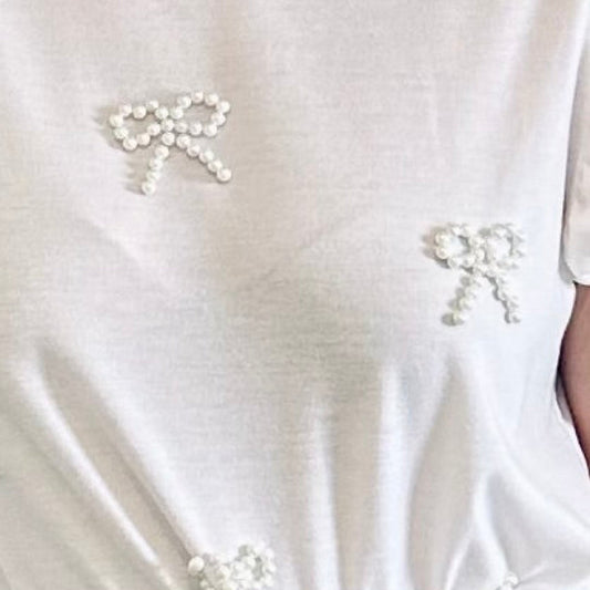 White top with bow details and beige pants with lace trim.
