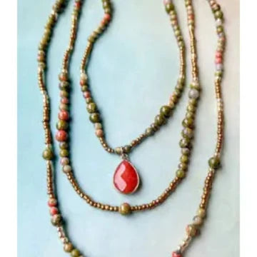 Two beaded necklaces with a red teardrop pendant on a light blue background