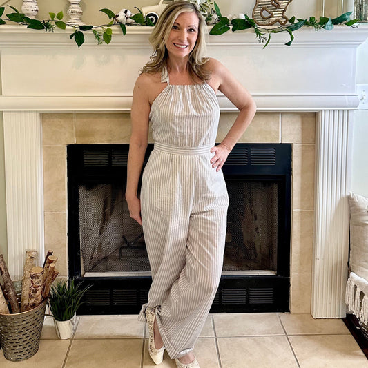 Woman in a white striped jumpsuit standing in front of a decorated fireplace.