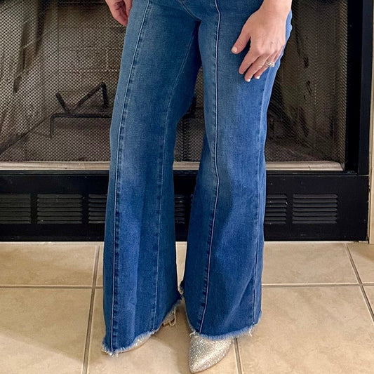 Person wearing blue jeans standing in front of a fireplace.