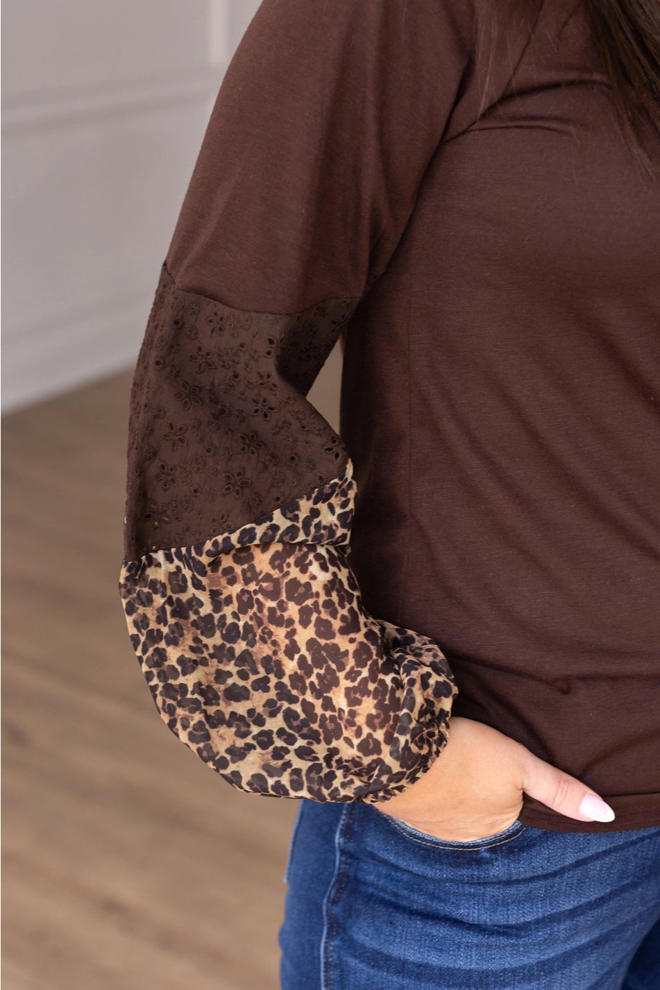 Leopard Sleeve Top is a stylish and versatile piece that adds a touch of boldness to your everyday look. Featuring a relaxed fit, this top stands out with its solid body and contrasting leopard-print sleeves with eyelet detailing.