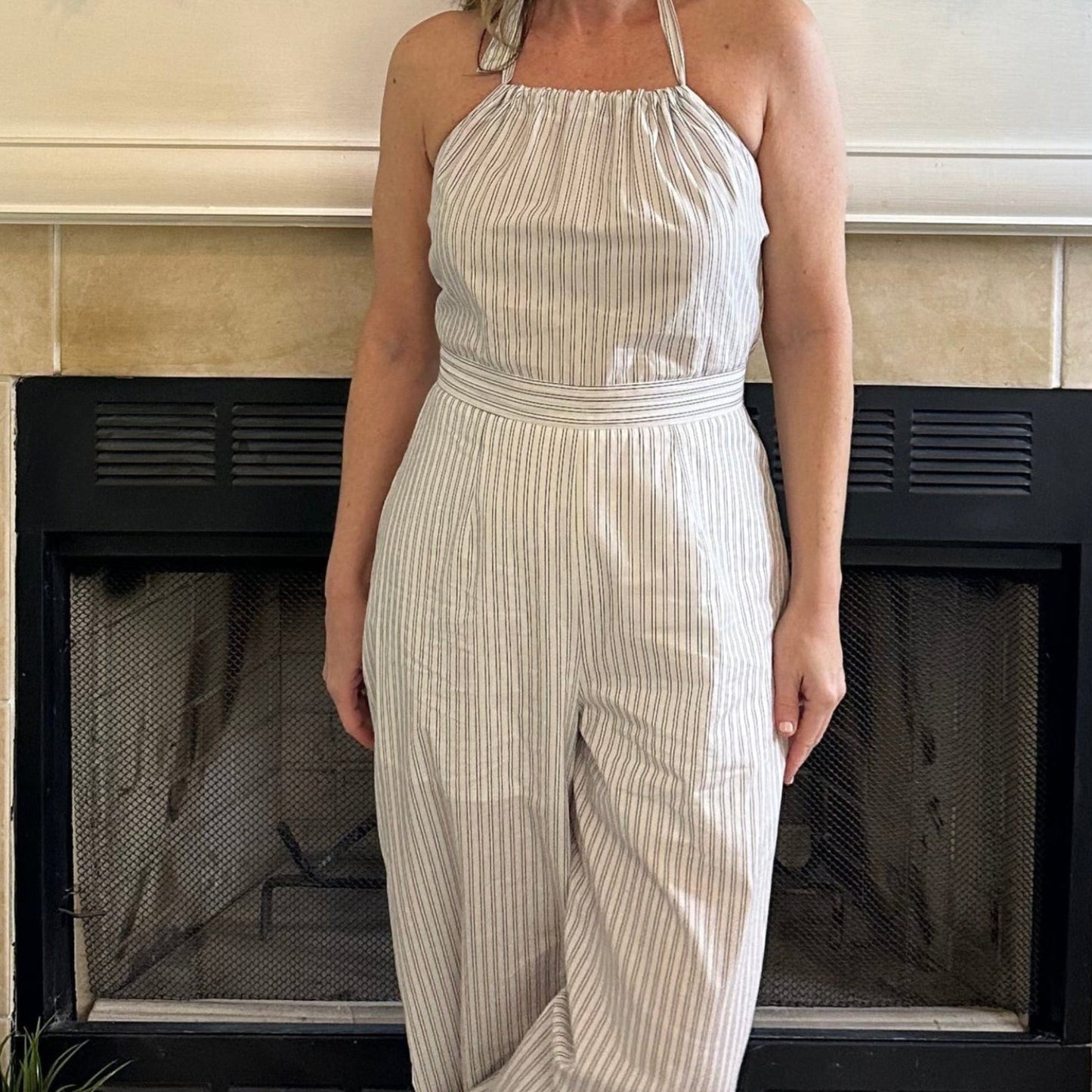 Woman in a white dress standing in front of a fireplace with decorative elements.