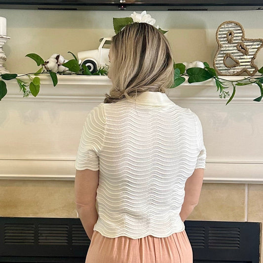 Woman standing in front of a decorated fireplace with greenery and candles.