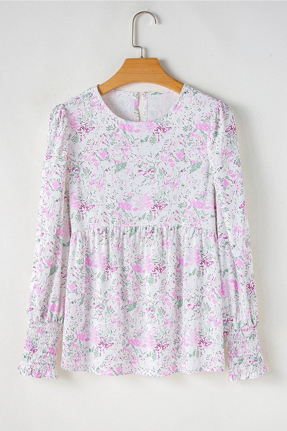 Floral Print Blouse. This blouse features a charming floral print in soft, pastel tones. The design includes a flattering V-neckline, long puffed sleeves with smocked cuffs, and a relaxed, flowy fit.