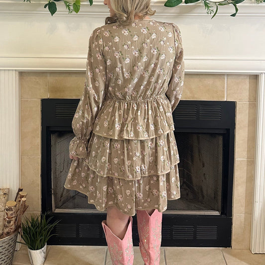 Person wearing a floral dress and pink cowboy boots standing in front of a fireplace.