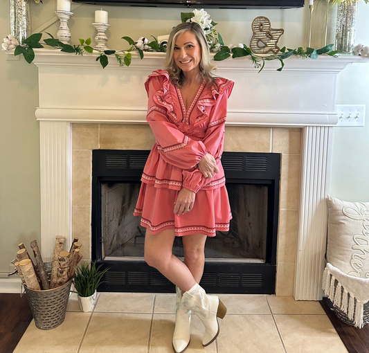 Woman in a pink dress standing in front of a fireplace