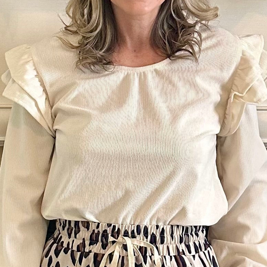 Beige blouse with ruffled sleeves worn by a person, with a neutral background