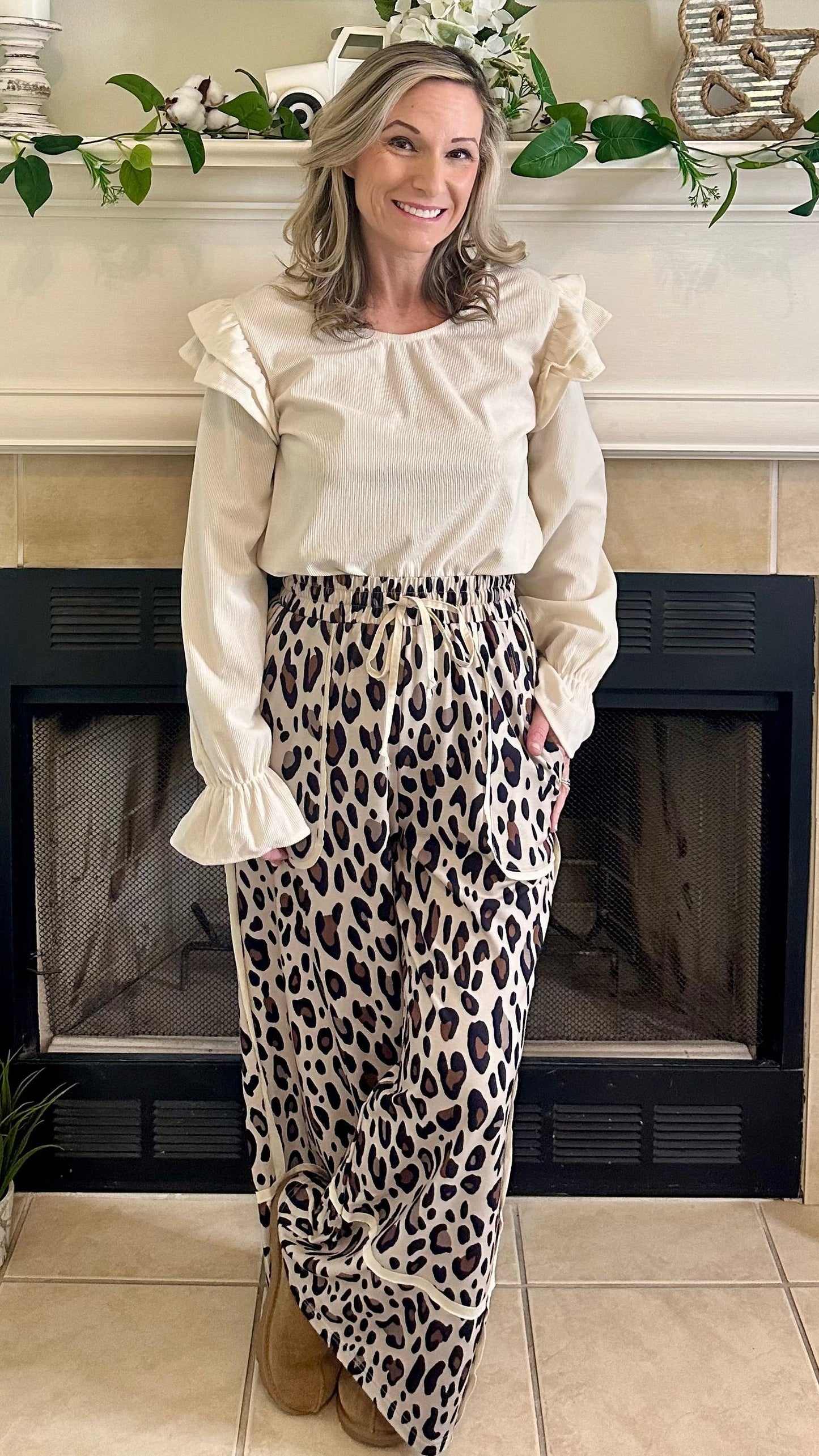 Woman standing in a living room with a fireplace and decorative mantel.
