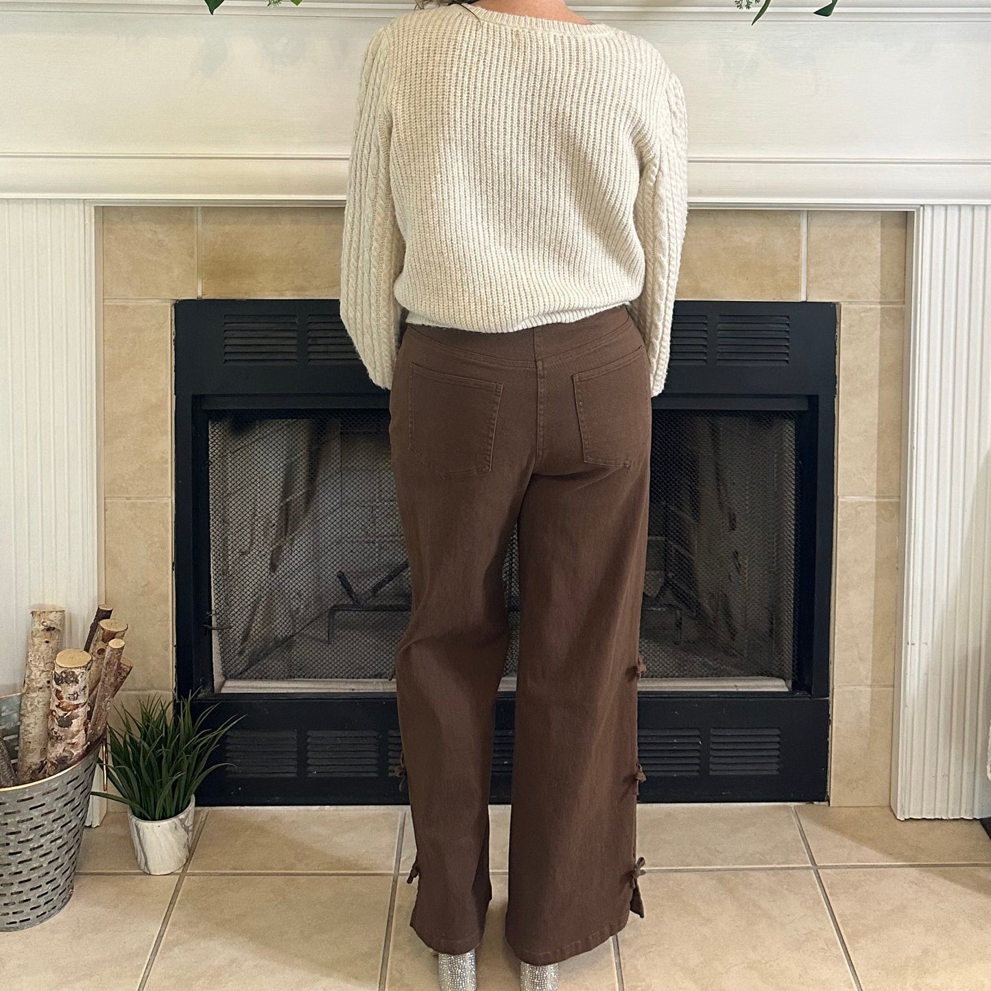 Person standing in a living room with a television, fireplace, and decorative items.