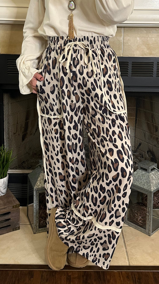 Person wearing leopard print pants standing in front of a fireplace.