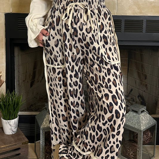 Person wearing leopard print pants standing in front of a fireplace.