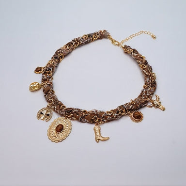 This necklace features a fabric-wrapped band adorned with intricate gold pendants, including cowboy boots, hats, and horseshoes.