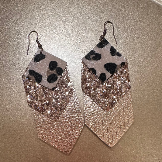 Pair of earrings with leopard print and glittery design on a metallic surface