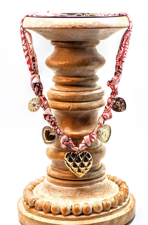 This romantic fabric-wrapped choker features multiple gold-tone heart charms.