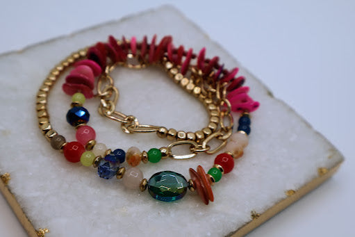 This colorful and versatile piece is designed for effortless style, transforming seamlessly between a stretch bracelet and a vibrant necklace. Featuring a lively mix of beads, gold-tone accents, and shell-like chips.