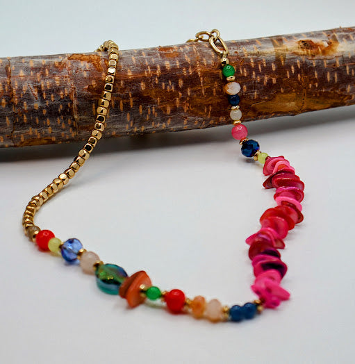 Colorful beaded necklace with gold chain on a wooden branch