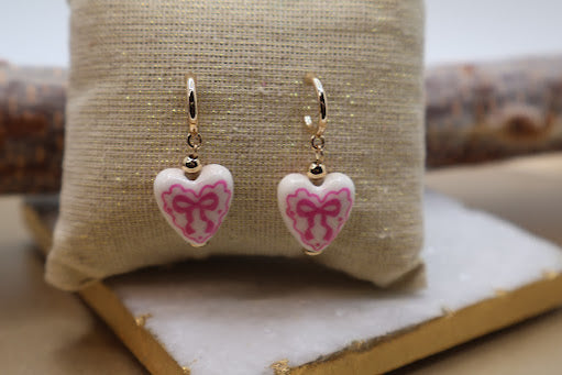 Heart-shaped earrings with pink bows.