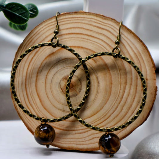 A pair of fishhook dangle earrings feature a delicate hoop design adorned with a single bead made from natural stone.