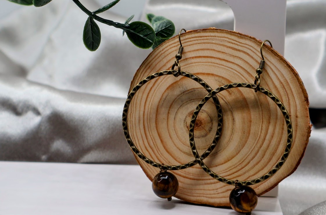 Pair of hoop earrings with brown beads on a wooden display