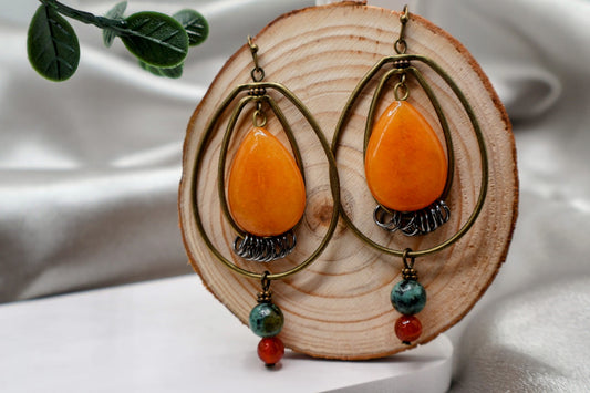 A pair of Boho earrings featuring intricate dangling detailed pendants, these lightweight earrings are designed for comfort and style. The unique oval wire design adds a modern touch, while the vibrant colors make them perfect for any occasion. Measuring 3 inches in length, these earrings are sure to make a statement without weighing you down.