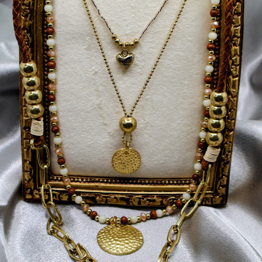 Gold necklace with decorative elements on a textured surface