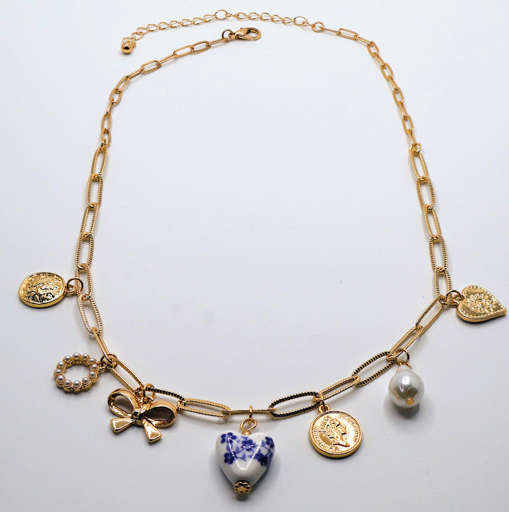 Charm Necklace. This gold-tone necklace features a combination of unique, eye-catching charms, including a delicate pearl, a floral-inspired heart, and intricate coin pendants.