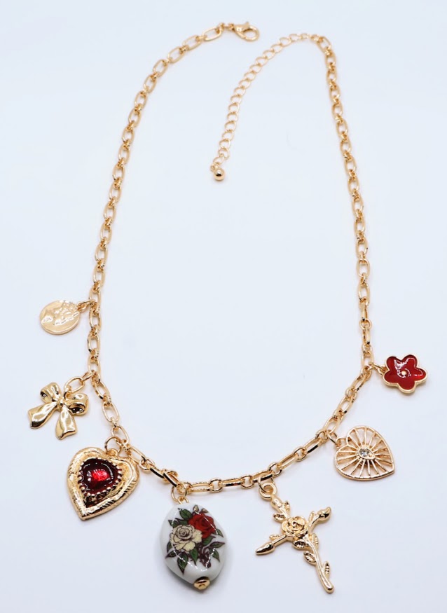 Vintage Charm Necklace. Featuring a gold-tone chain adorned with an exquisite collection of charms, including a rose-adorned heart, a dainty bow, a floral oval pendant, and a radiant cross.
