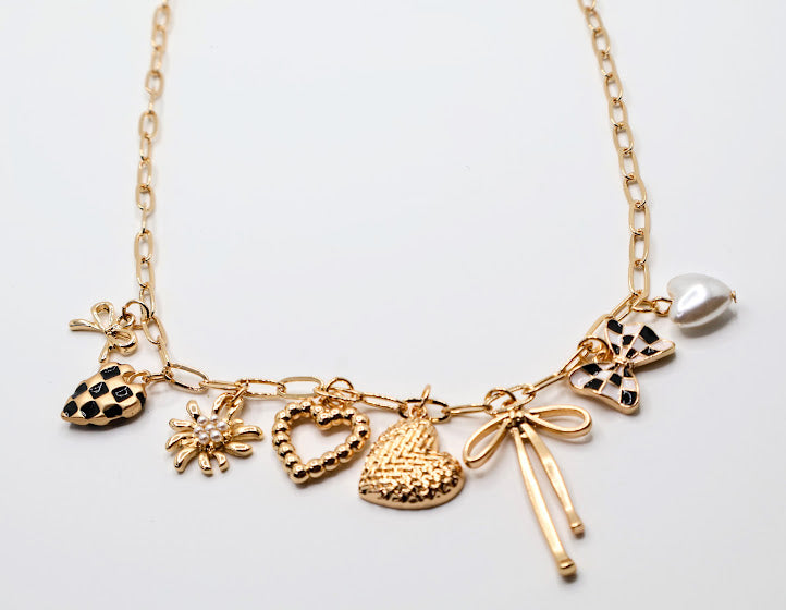 Charm Cascade Necklace  Featuring a gold-tone chain adorned with charming pendants, including textured hearts, a delicate bow, a luminous pearl, and checkered-inspired accents.