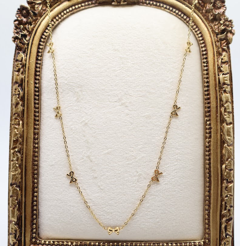 Gold Bow Charm Necklace is a delicate and timeless accessory that exudes elegance and charm. Featuring three dainty bow-shaped accents.