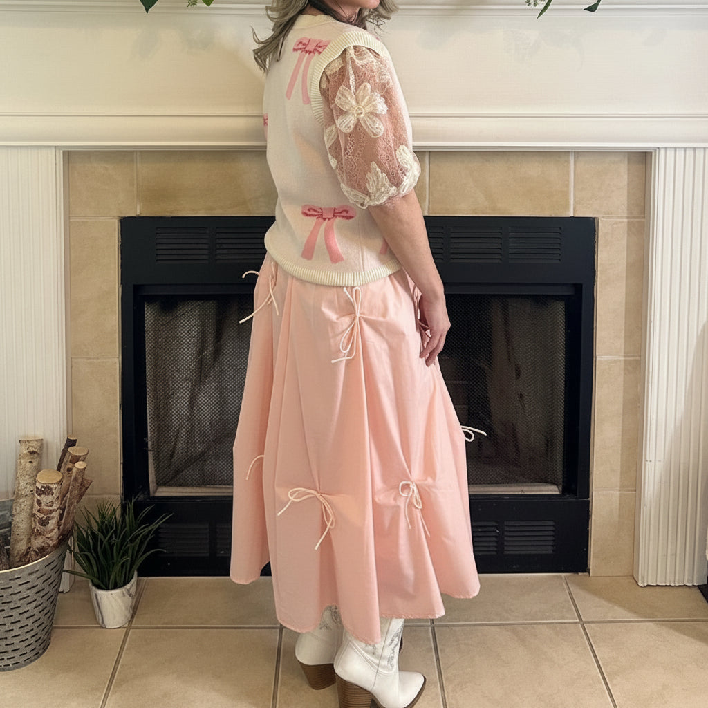Blush Pink Bow Detail Midi Skirt is a feminine and elegant piece designed to elevate your wardrobe. This flowy midi skirt features delicate bow accents throughout.