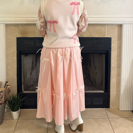Blush Pink Bow Detail Midi Skirt is a feminine and elegant piece designed to elevate your wardrobe. This flowy midi skirt features delicate bow accents throughout.