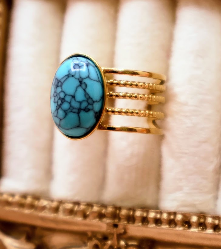 Ring embodies the essence of natural beauty and bohemian elegance. Featuring an oval turquoise stone with captivating veining, set on a layered gold-tone band.