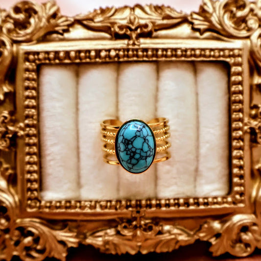 Ring embodies the essence of natural beauty and bohemian elegance. Featuring an oval turquoise stone with captivating veining, set on a layered gold-tone band.