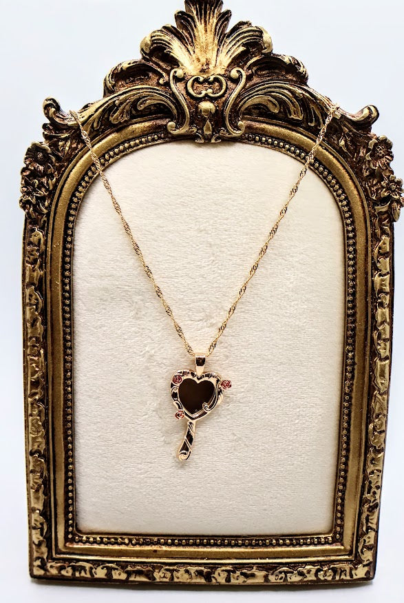 Rose Mirror Necklace is a stunning symbol of elegance and charm. The heart-shaped pendant, designed as a petite mirror, features intricate gold swirls and delicate pink rose accents that add a romantic touch.