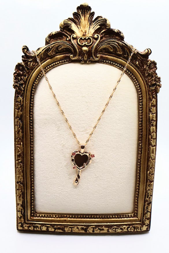 ose Mirror Necklace is a stunning symbol of elegance and charm. The heart-shaped pendant, designed as a petite mirror, features intricate gold swirls and delicate pink rose accents that add a romantic touch.
