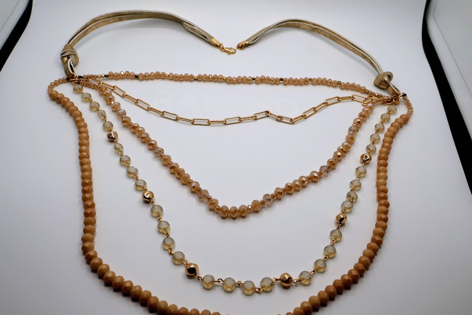 Multi-layerded Necklace featuring strands of ivory-toned beads, shimmering chains, and delicate gold accents.